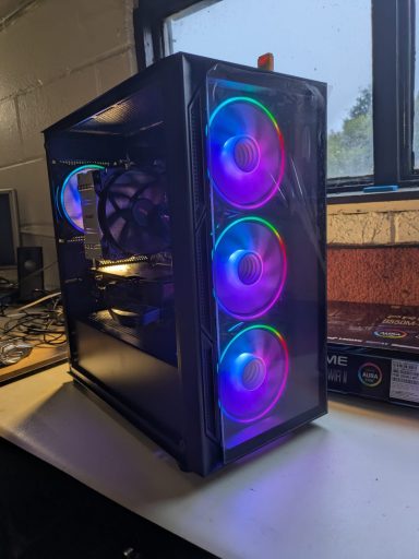 Ryzen 5 5600X/32GB DDR4/1TB SSD/RX7600 8GB Black computer case with three illuminated RGB fans in front.
