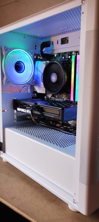 Ryzen 5 5600/32GB DDR4/1TB SSD/RTX3060 12GB A white PC case showcasing internal components and colourful RGB lighting.