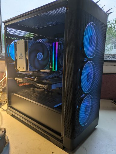 Ryzen 5 5600/32GB DDR4/1TB SSD/RX7600 8GB A gaming PC with transparent case, RGB fans, and glowing components inside.