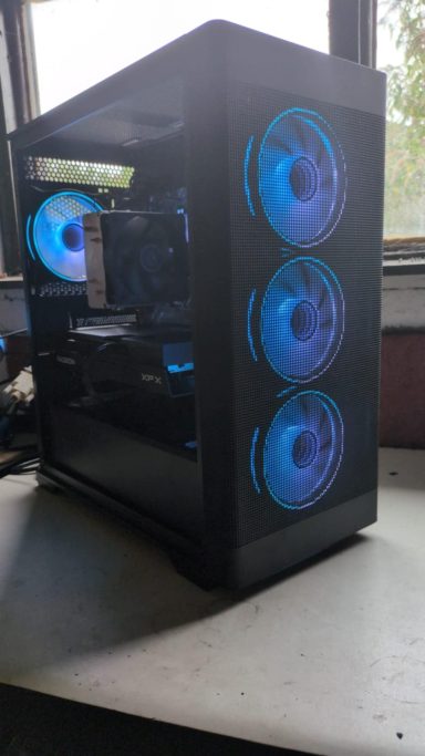 Ryzen 5 5600/32GB DDR4/1TB SSD/RX9060 XT 8GB A black PC case with blue LED fans and a glass side panel.